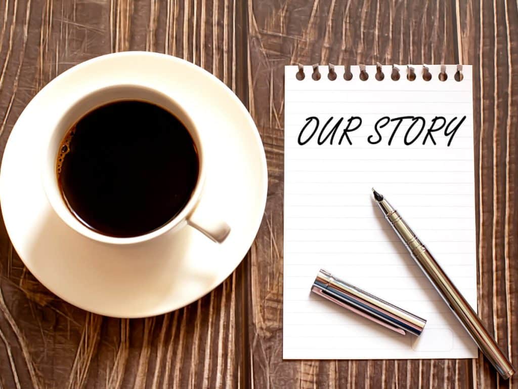 coffee on table beside pen and notepad that reads 'our story'